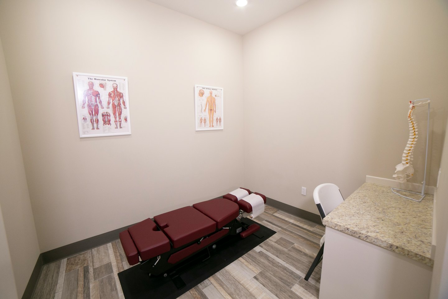 Sala di visita chiropratica con lettino e grafici anatomici.